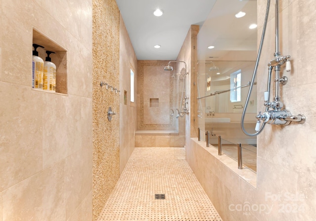 bathroom featuring a tile shower, tile patterned floors, tile walls, and a healthy amount of sunlight