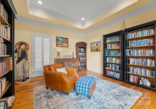 sitting room featuring a tray ceiling, crown molding, and wood-type flooring