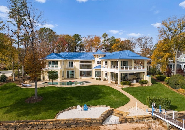 back of house featuring a balcony, a patio area, and a lawn