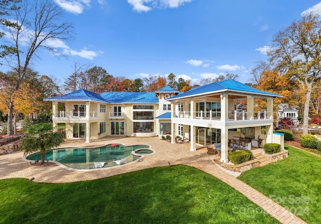 rear view of property featuring a lawn, a patio area, a balcony, and a pool with hot tub