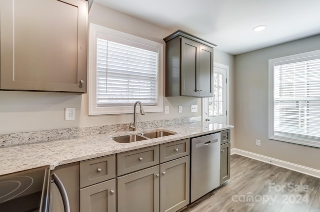 kitchen with light stone counters, sink, appliances with stainless steel finishes, and light hardwood / wood-style flooring