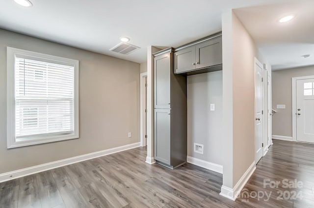 unfurnished bedroom featuring hardwood / wood-style flooring, a closet, and multiple windows