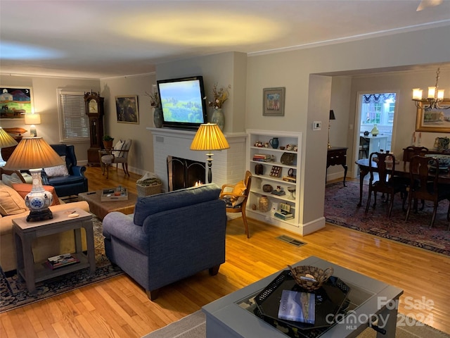 living room featuring a fireplace, a chandelier, and light hardwood / wood-style flooring