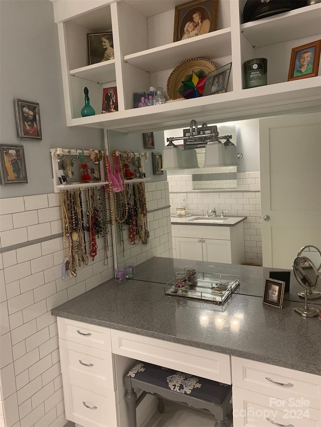 kitchen featuring white cabinets, backsplash, tile walls, and sink