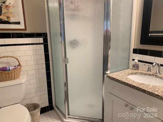 bathroom with an enclosed shower, vanity, tile patterned flooring, and tile walls