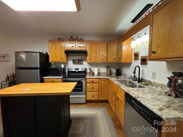 kitchen with sink, stainless steel appliances, decorative light fixtures, and wooden counters