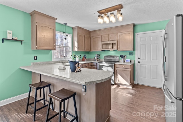 kitchen with pendant lighting, stainless steel appliances, a kitchen bar, dark hardwood / wood-style flooring, and kitchen peninsula