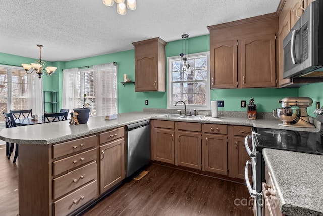 kitchen featuring stainless steel appliances, kitchen peninsula, sink, and hanging light fixtures