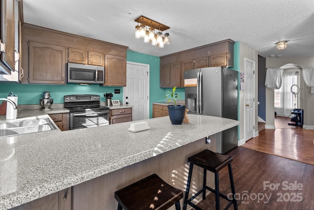 kitchen with stainless steel appliances, sink, a breakfast bar, and kitchen peninsula