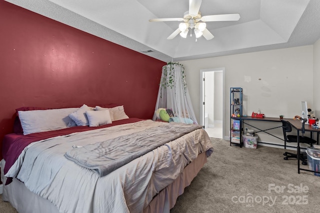 bedroom with light carpet, ceiling fan, and a tray ceiling