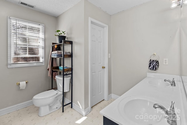 bathroom with vanity, toilet, and a textured ceiling