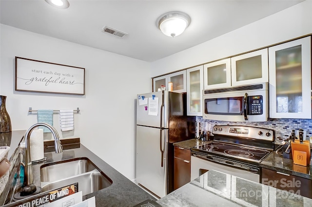 kitchen with stainless steel appliances, tasteful backsplash, dark stone countertops, and sink