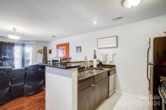 kitchen with kitchen peninsula, dark brown cabinets, stainless steel appliances, and sink