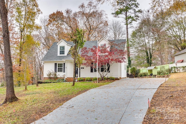 new england style home featuring a shed and a front yard