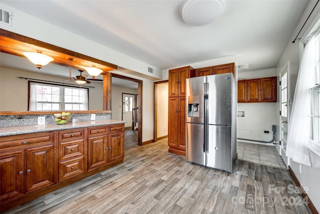 kitchen with ceiling fan, light hardwood / wood-style floors, light stone counters, and stainless steel fridge with ice dispenser