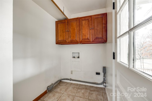 laundry area with light tile patterned flooring, cabinets, and hookup for a washing machine