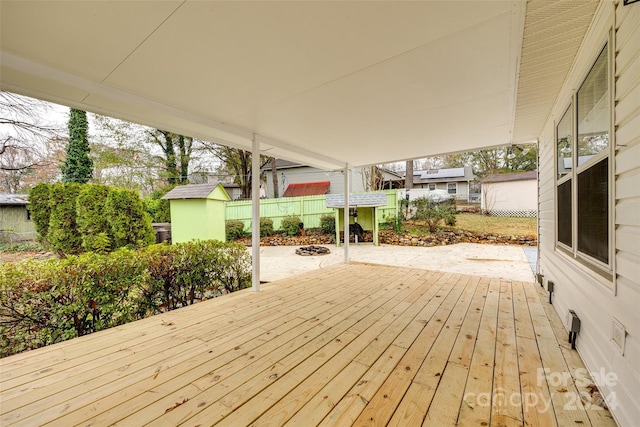 wooden deck featuring a patio area, a fire pit, and a storage shed