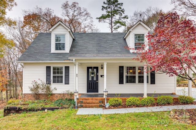 cape cod house featuring covered porch and a front yard