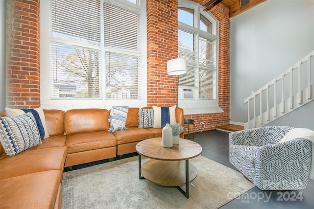 living room featuring beam ceiling, cooling unit, brick wall, and a high ceiling