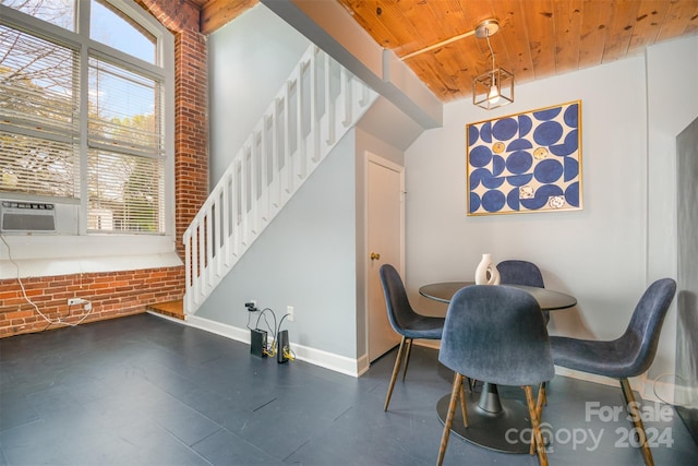 dining area with wooden ceiling, cooling unit, a healthy amount of sunlight, and brick wall