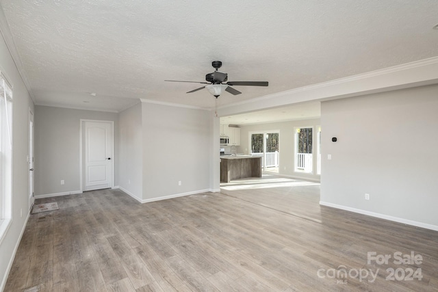 unfurnished living room with sink, ceiling fan, ornamental molding, a textured ceiling, and light hardwood / wood-style floors