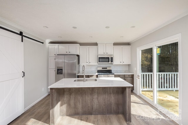 kitchen with white cabinets, a barn door, sink, and stainless steel appliances