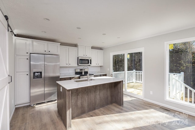 kitchen with white cabinetry, plenty of natural light, an island with sink, and appliances with stainless steel finishes