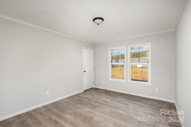 spare room with hardwood / wood-style floors, a textured ceiling, and ornamental molding