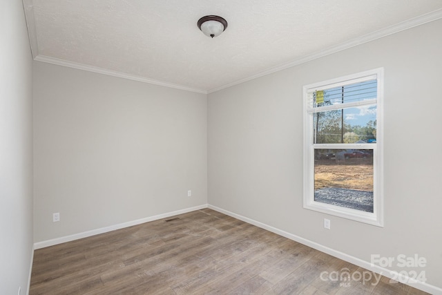 spare room featuring hardwood / wood-style floors, a textured ceiling, and ornamental molding