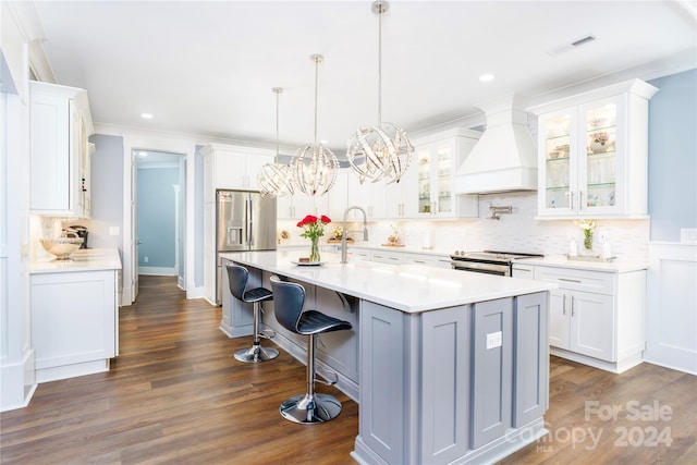 kitchen with white cabinets, premium range hood, dark wood-type flooring, and a center island with sink