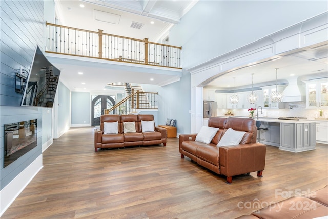 living room featuring hardwood / wood-style floors, plenty of natural light, sink, and crown molding