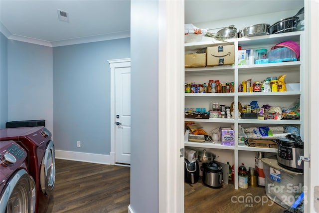 washroom featuring dark hardwood / wood-style floors, ornamental molding, and washing machine and clothes dryer