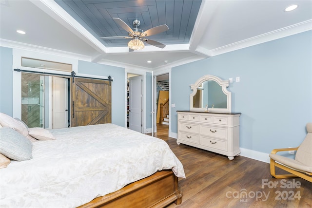 bedroom featuring ceiling fan, a spacious closet, a barn door, dark hardwood / wood-style flooring, and ornamental molding