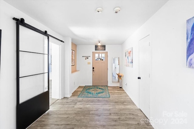 foyer entrance with light wood-type flooring and a barn door