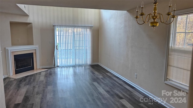 unfurnished living room with a notable chandelier and dark wood-type flooring