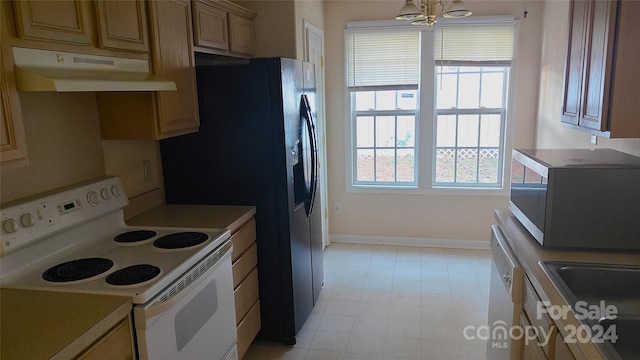 kitchen with light brown cabinetry, white appliances, and an inviting chandelier