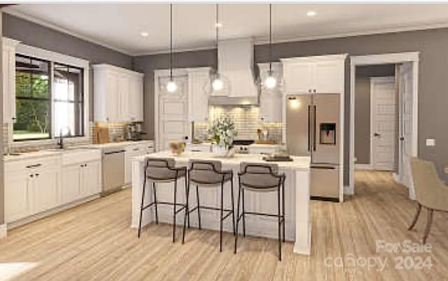 kitchen featuring stainless steel appliances, wall chimney range hood, pendant lighting, white cabinets, and a kitchen island