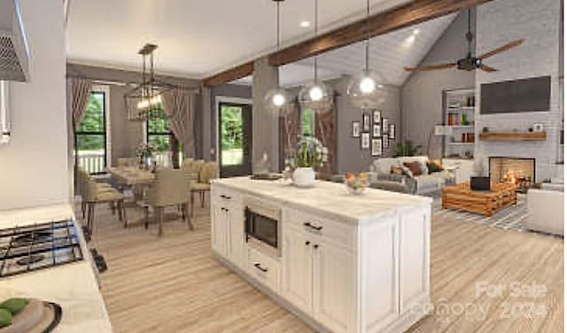 kitchen with vaulted ceiling with beams, a fireplace, a healthy amount of sunlight, and decorative light fixtures