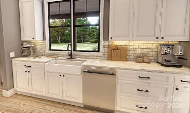 kitchen with light stone countertops, light wood-type flooring, backsplash, sink, and white cabinetry