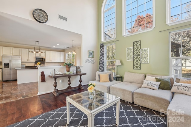 living room with dark wood-type flooring, a towering ceiling, and a healthy amount of sunlight