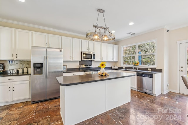 kitchen with pendant lighting, white cabinets, ornamental molding, and stainless steel appliances