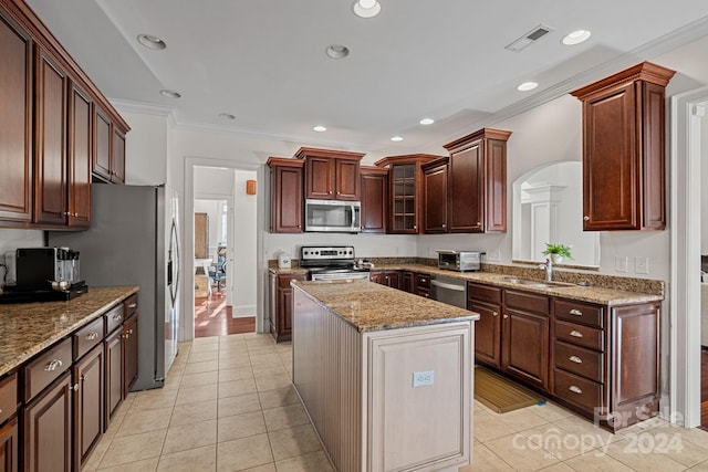 kitchen with ornamental molding, stainless steel appliances, sink, light tile patterned floors, and a center island