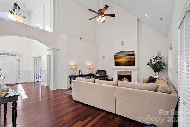 living room with ceiling fan, ornate columns, dark wood-type flooring, and high vaulted ceiling