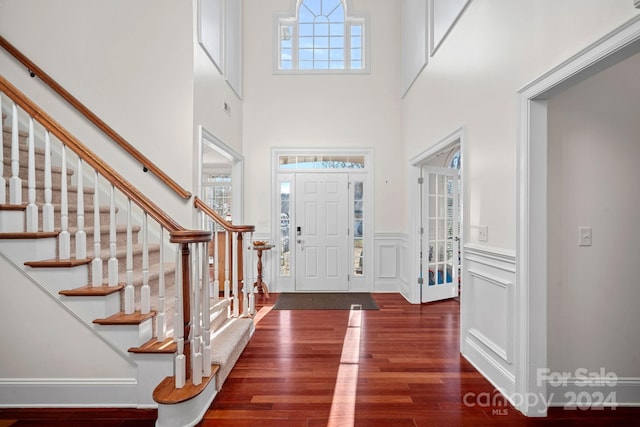 entrance foyer with dark wood-type flooring, a wealth of natural light, and a high ceiling