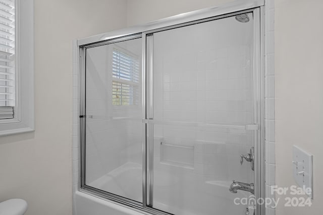 bathroom with toilet and combined bath / shower with glass door