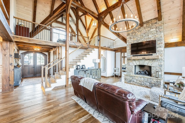 living room with high vaulted ceiling, french doors, light wood-type flooring, a fireplace, and a chandelier