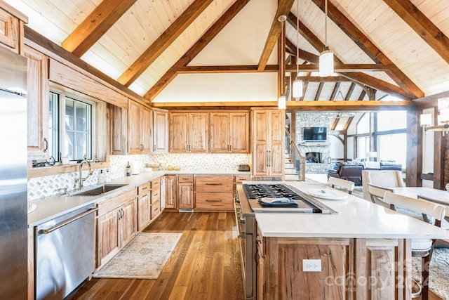 kitchen with beam ceiling, sink, stainless steel appliances, light hardwood / wood-style floors, and a fireplace