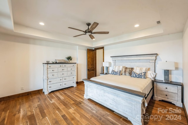 bedroom featuring a tray ceiling, ceiling fan, and hardwood / wood-style flooring