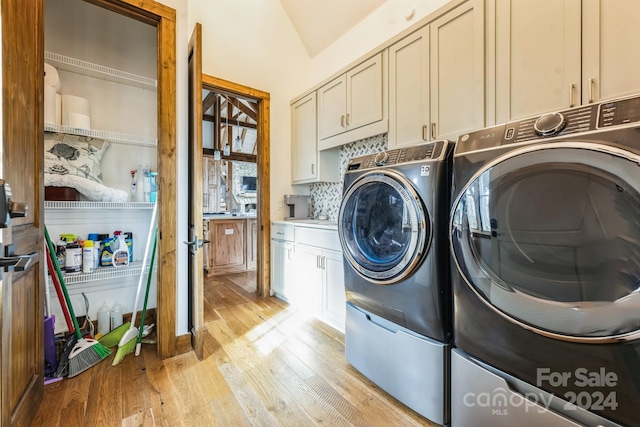 laundry area featuring cabinets, light wood-type flooring, and washing machine and dryer