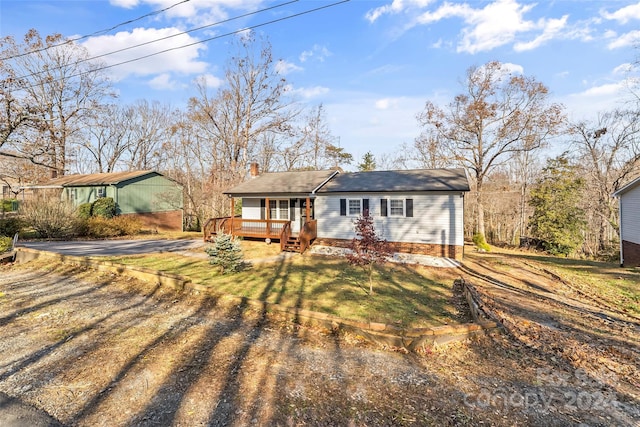 ranch-style home with a wooden deck and a front lawn